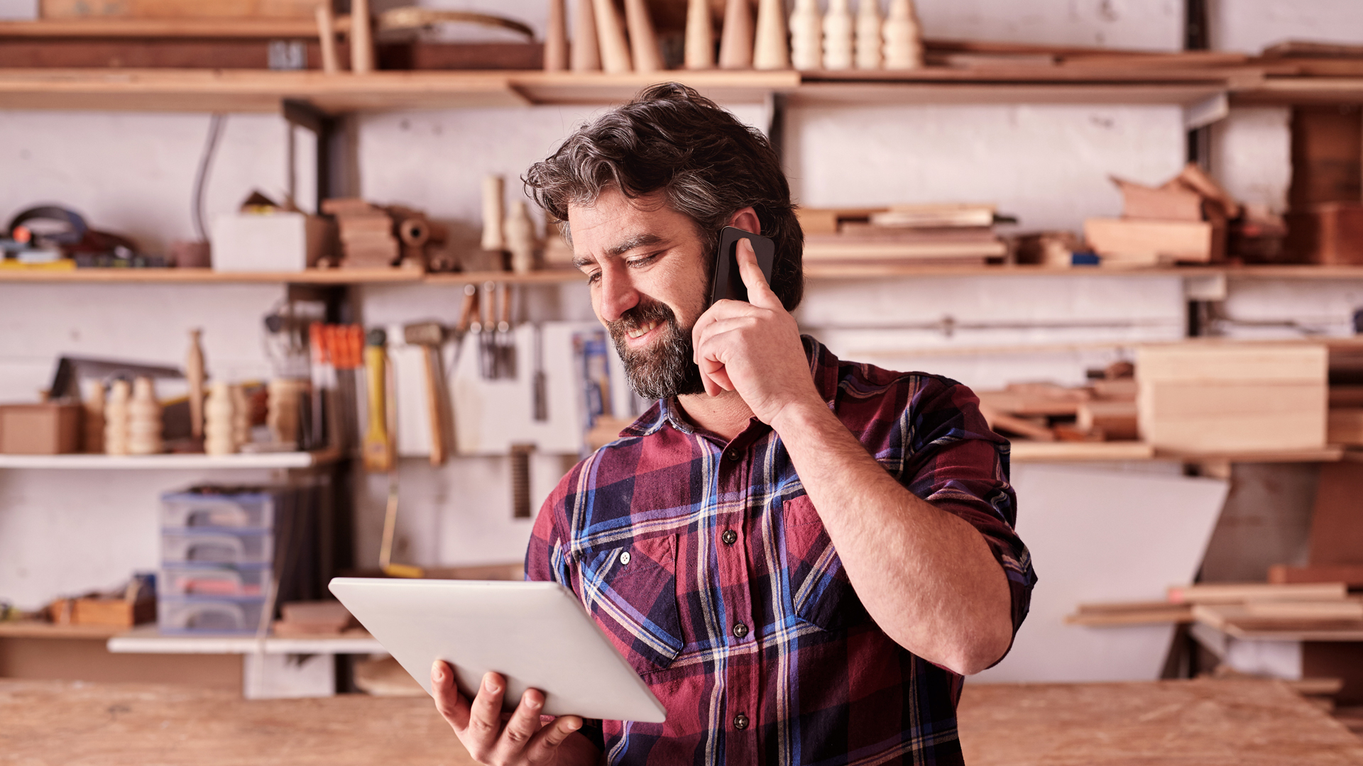 Empreendedor em sua oficina de marcenaria ao telefone com a Contrer.