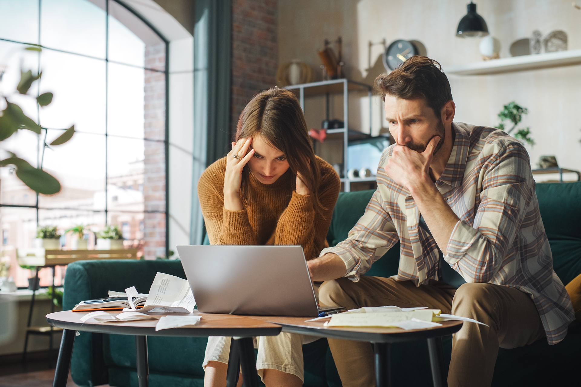 Casal empreendedor trabalhando no computador em casa com expressão de stress.